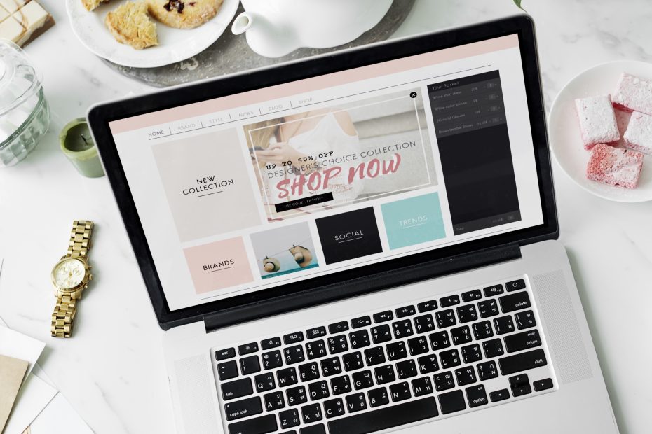un ordinateur portable posé sur un bureau avec des cookies et une tasse de thé